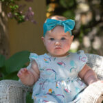 Baby girl with blue bow looking serious at Riverside Park