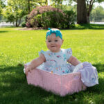 Baby girl in a basket surrounded by blooming spring flowers at Riverside Park