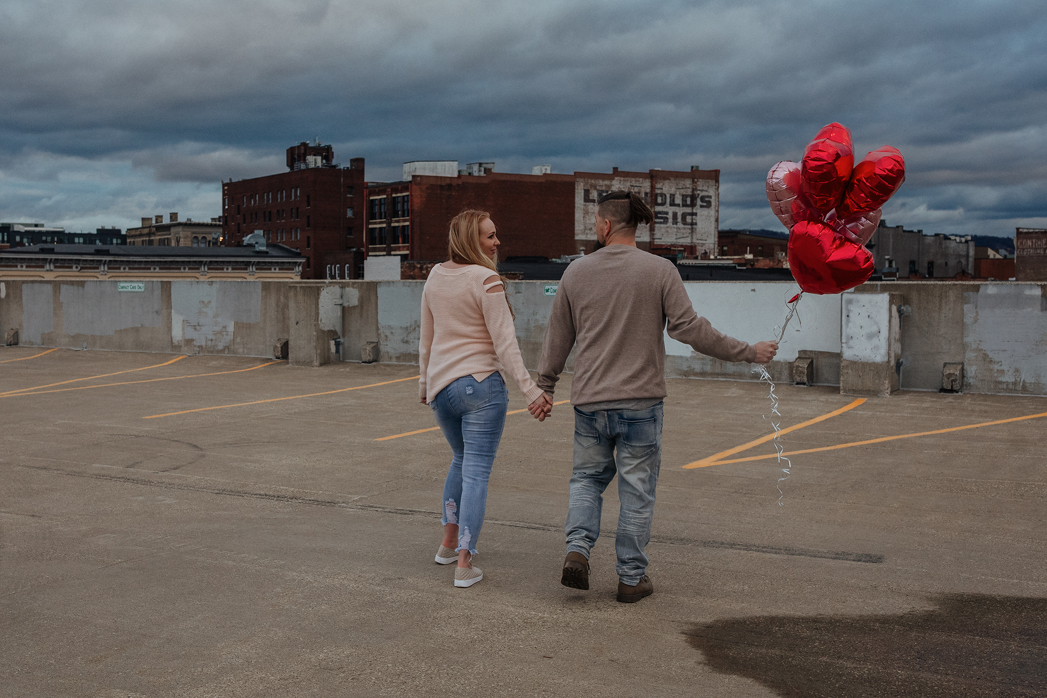 Playful urban engagement photos in La Crosse Wisconsin with city rooftop views