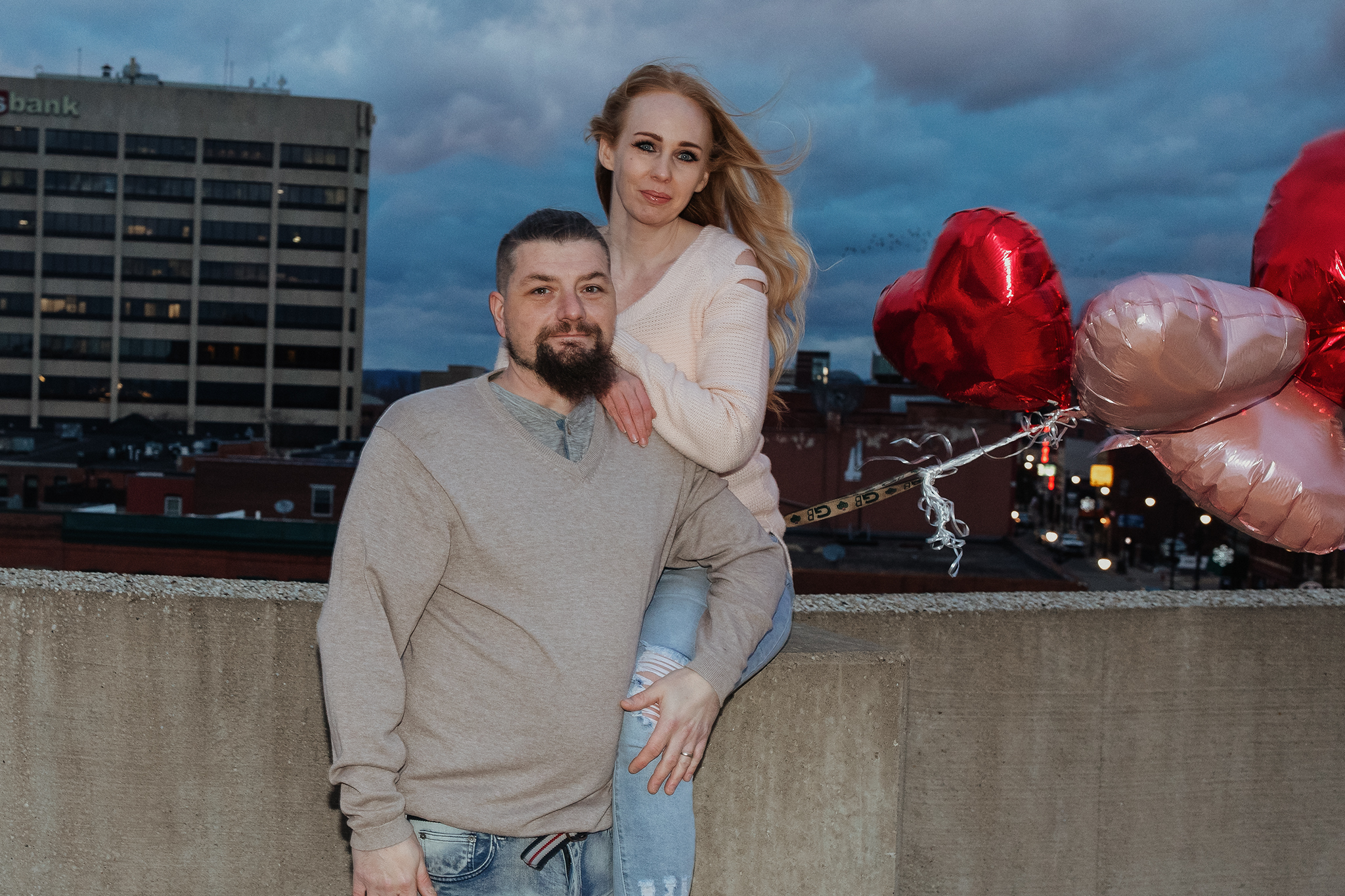 Downtown La Crosse engagement photography with heart balloons and city skyline