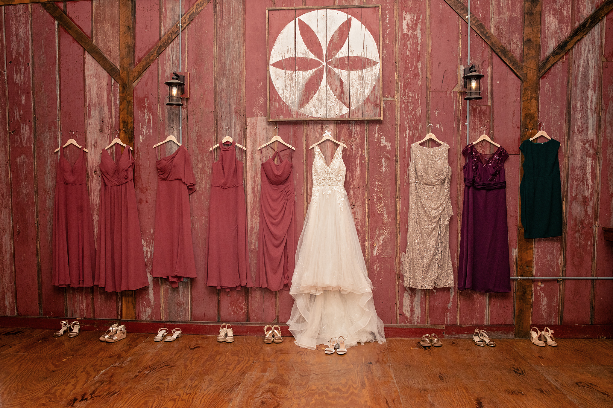 Bridal gown and bridesmaids dresses hanging in rustic barn wedding setting in La Crosse Wisconsin
